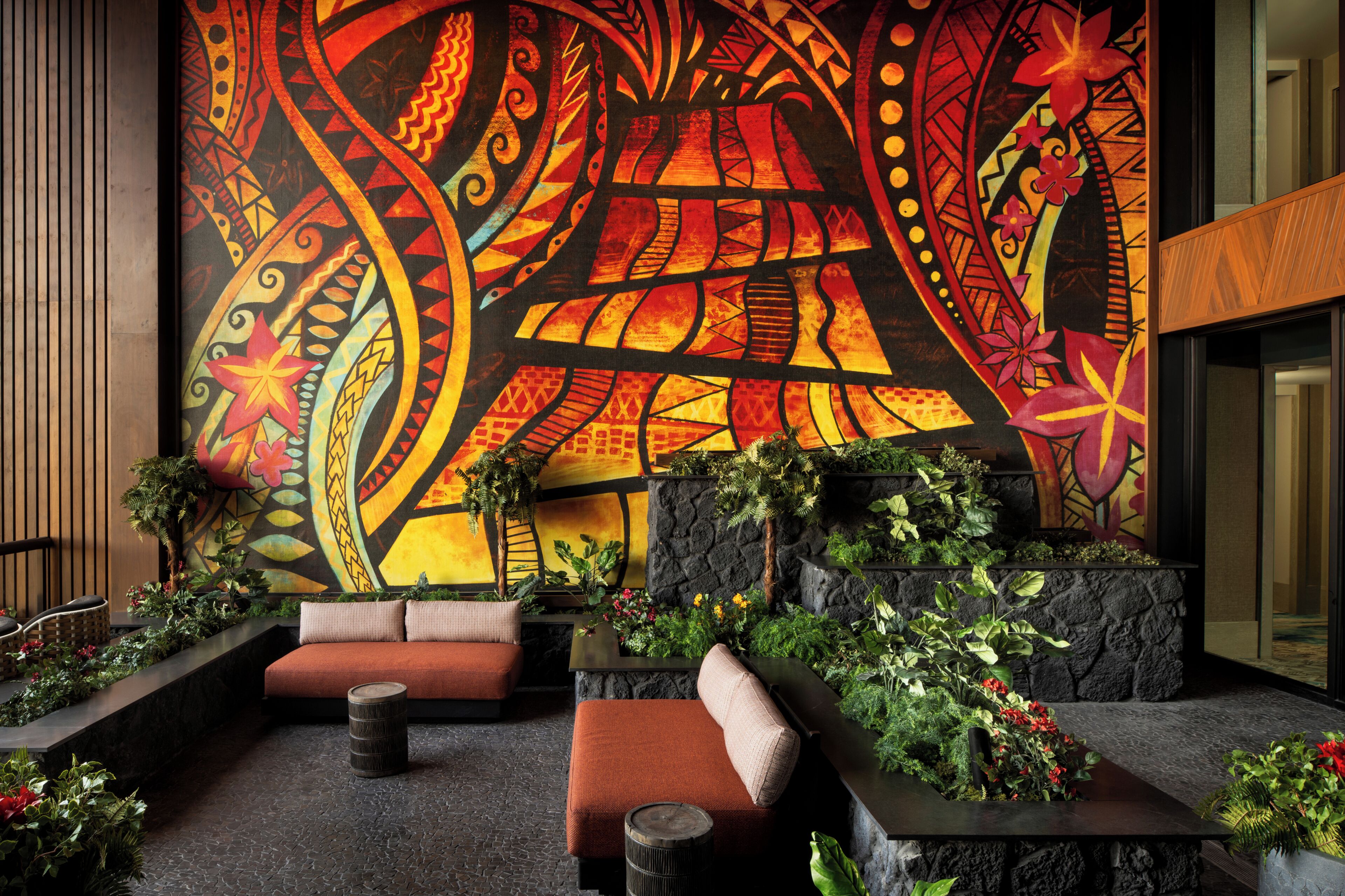 A lobby with a large mural, seating areas, and indoor plants.
