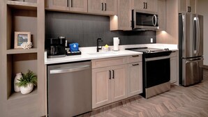 Une cuisine moderne dotée d’appareils électroménagers en acier inoxydable, de meubles en bois et d’un parquet disposé en motif à chevrons.