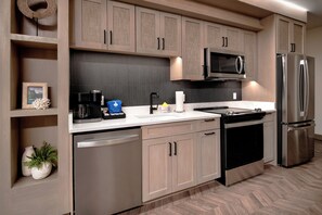 Una cocina moderna con electrodomésticos de acero inoxidable, armarios de madera y un suelo con patrón de espiga.