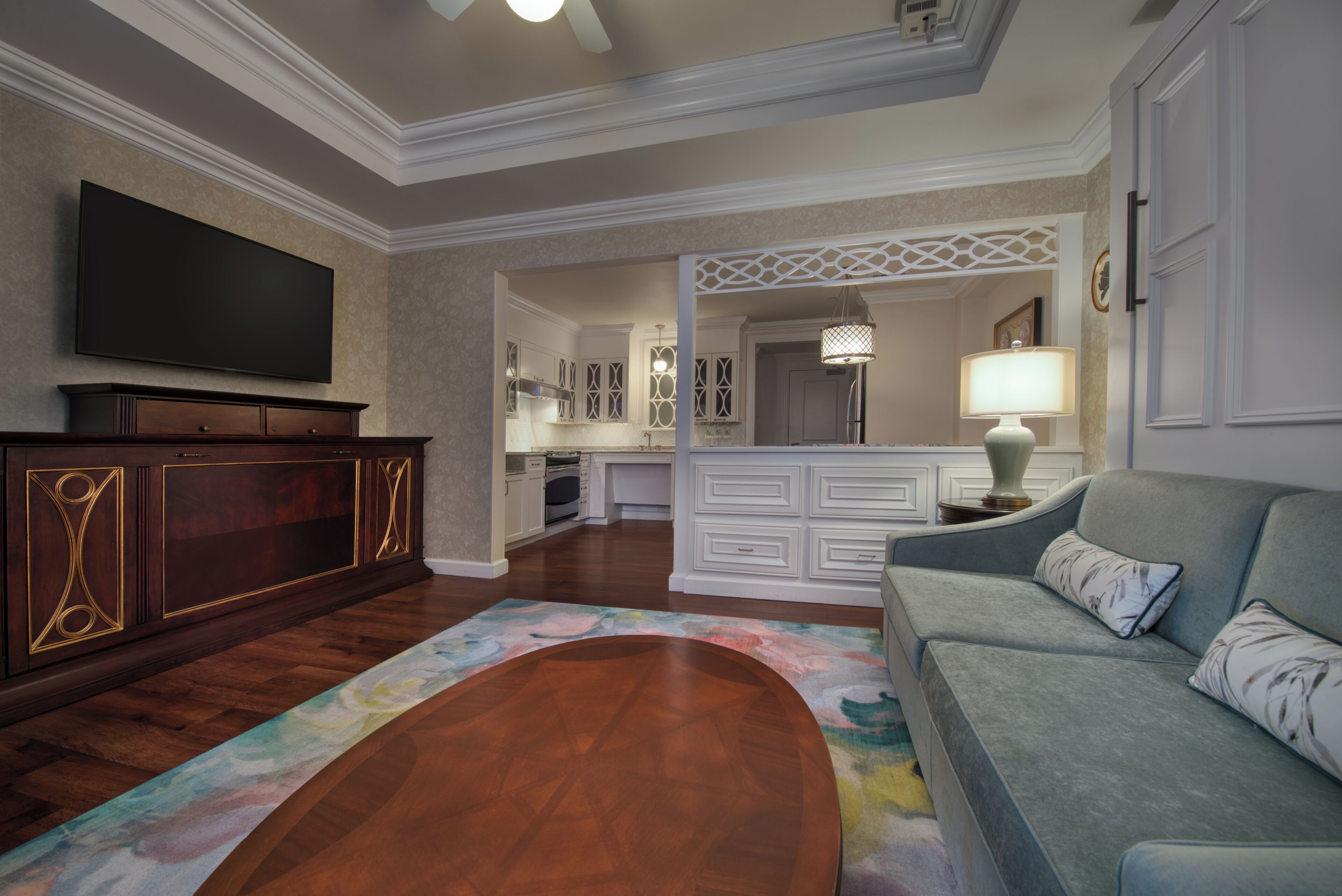 Een woonkamer met een flatscreen televisie, een bank, een salontafel en een keuken op de achtergrond.