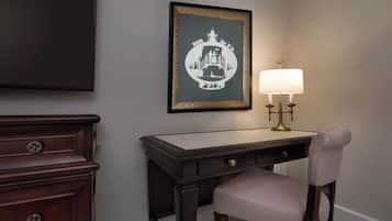 A dark wood desk with a lamp, a framed picture, and a chair.