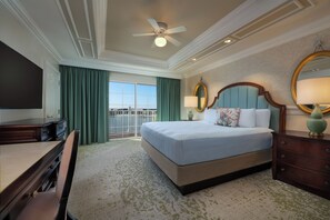 A hotel room with a large bed, a desk, a chair, a television, a ceiling fan, and a view of the outdoors. - The Villas At Disney's Grand Floridian Resort & Spa (Lake Buena Vista)