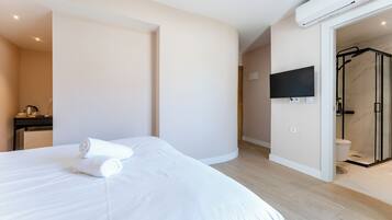 A hotel room with a bed, a TV mounted on the wall, and a shower area.