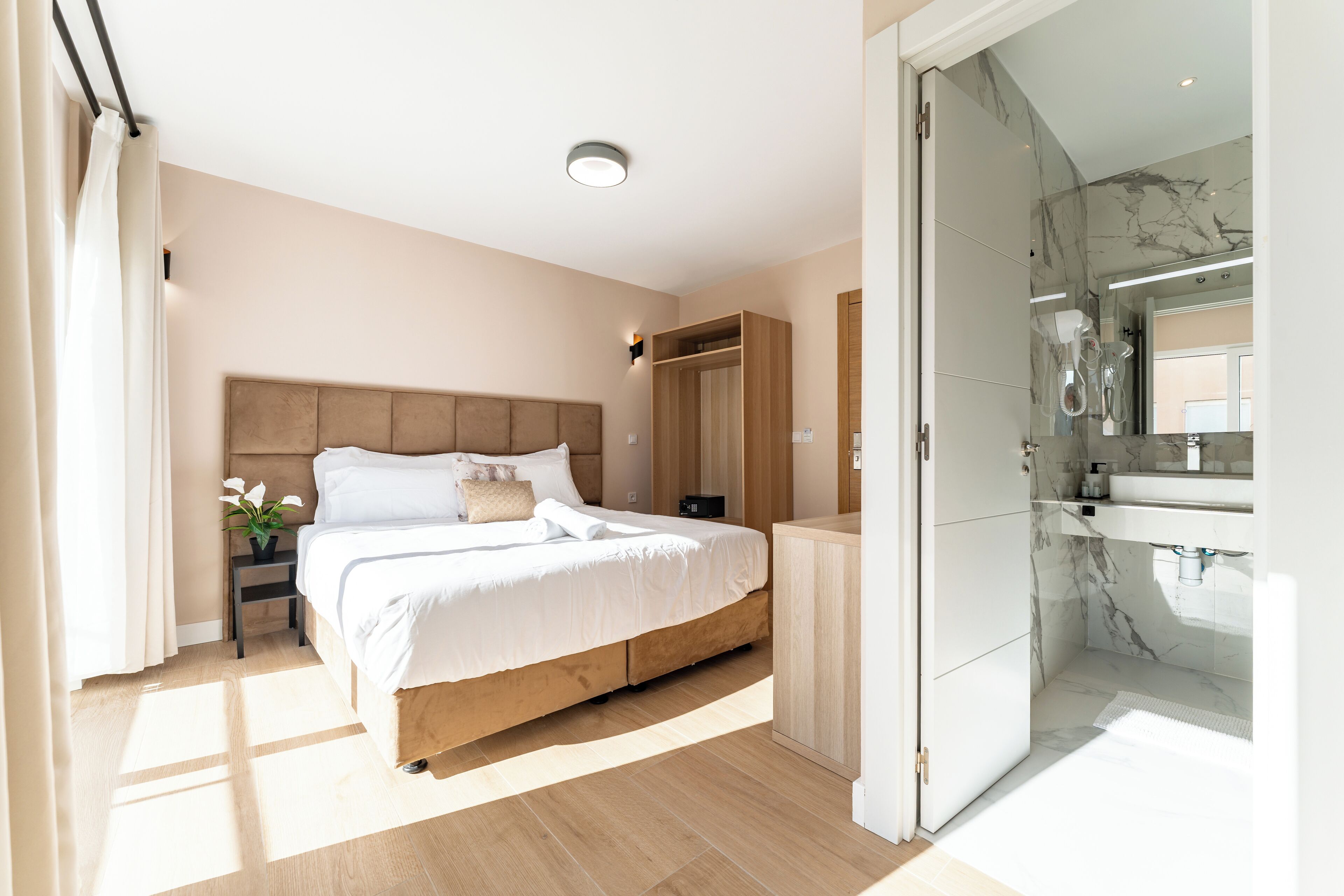 Et moderne soveværelse med en træseng, et natbord med en plante, et walk-in closet og et badeværelse med en marmorbruser.
