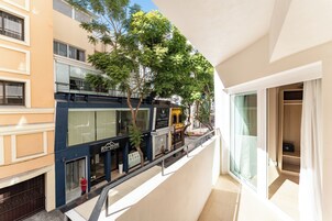 A modern building with a glass facade, a balcony with a railing, and a view of the street below.