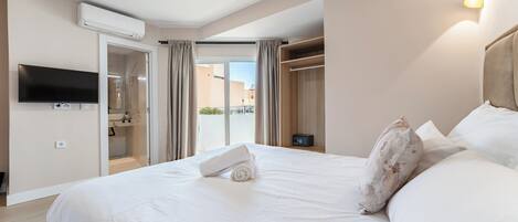 Une chambre d’hôtel avec un grand lit, un téléviseur fixé au mur, un appareil de climatisation, une armoire et une vue sur l’extérieur grâce à une porte vitrée.