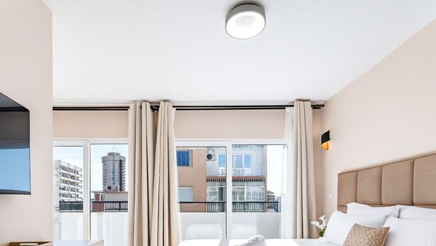 A modern hotel room with a large bed, a wooden desk, a flat-screen TV, and a balcony with curtains. - blanca maris (Fuengirola)