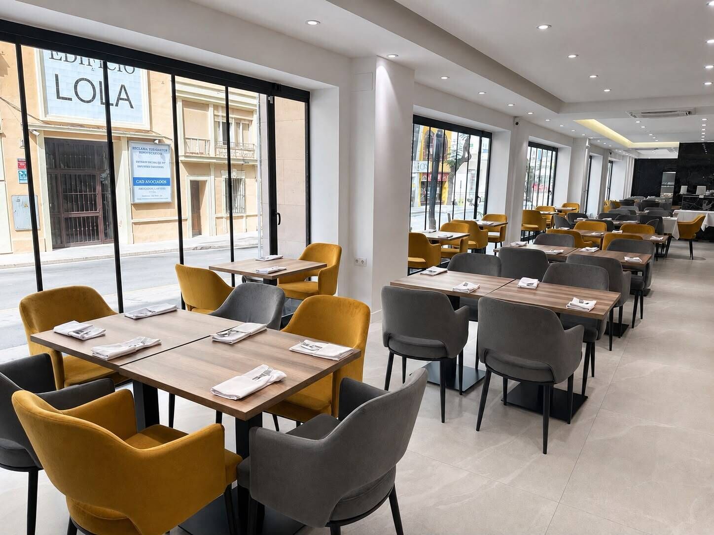 A modern dining area with tables and chairs, large windows, and a view of the street.