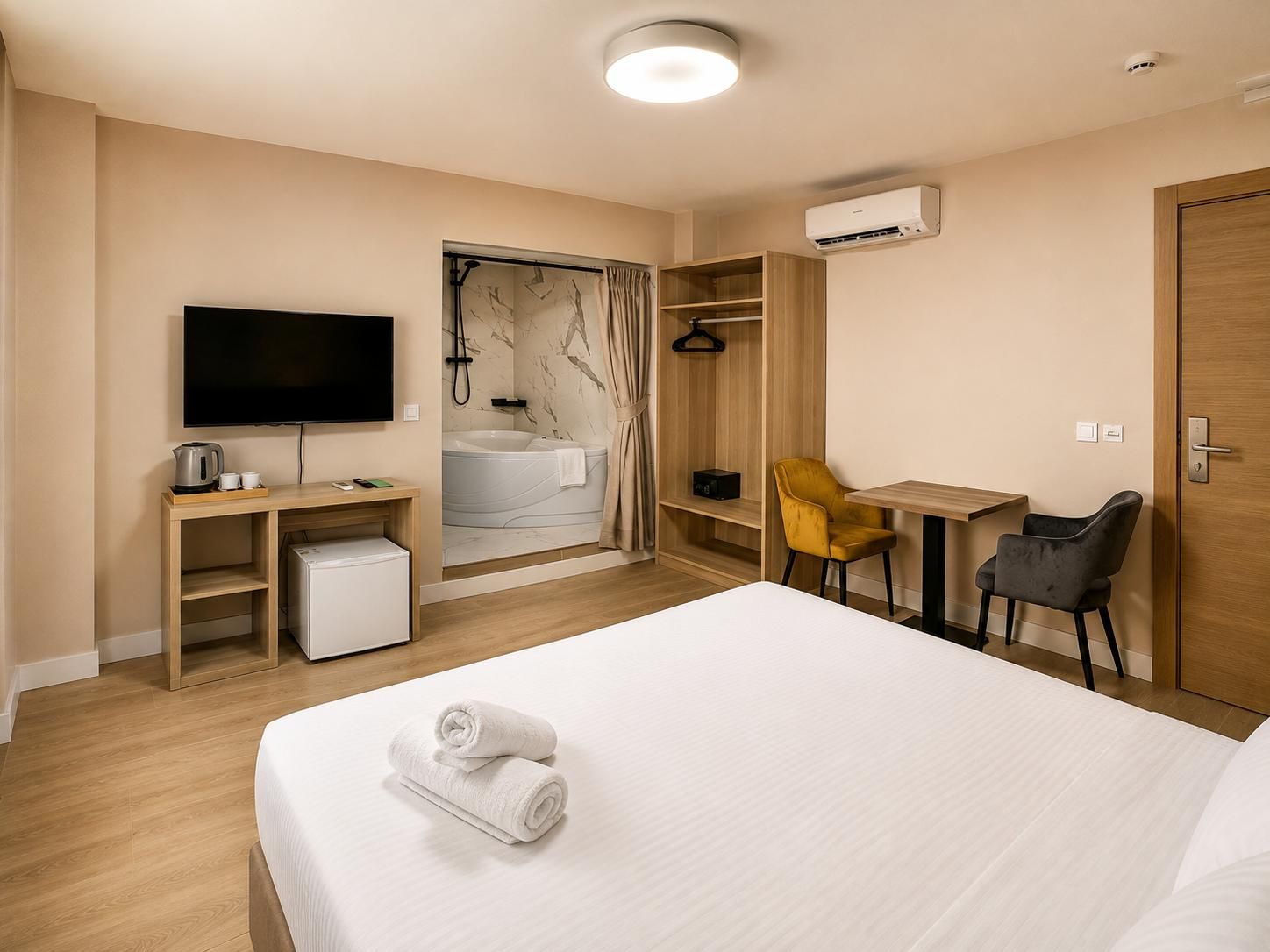 Et hotelværelse med seng, skrivebord, stol, fjernsyn, brusebad og aircondition.