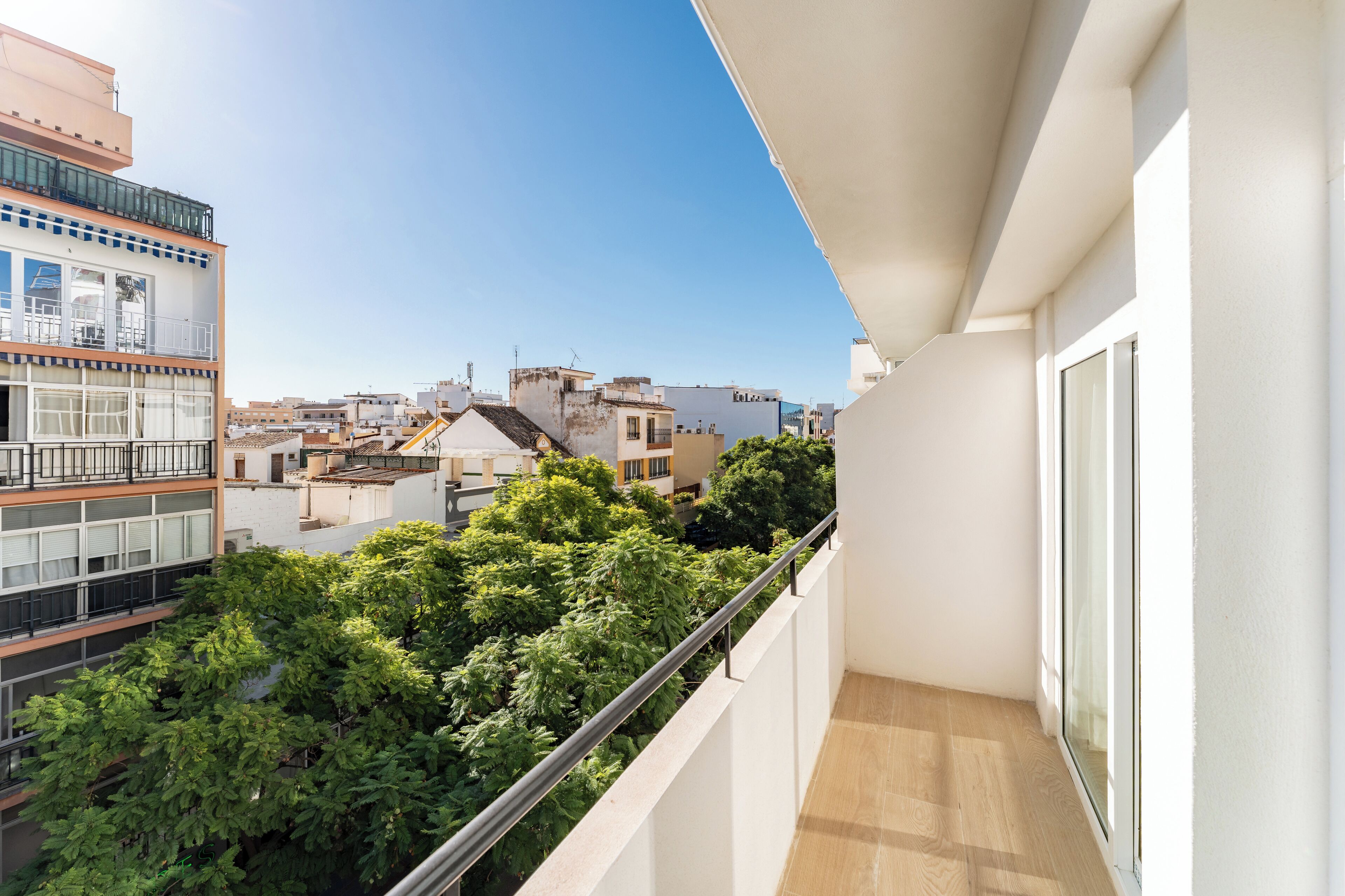 A balcony with a view of neighboring buildings and trees.