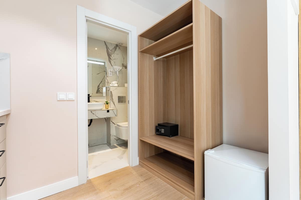 A modern bathroom with a marble backsplash, wooden shelving, and a white radiator.