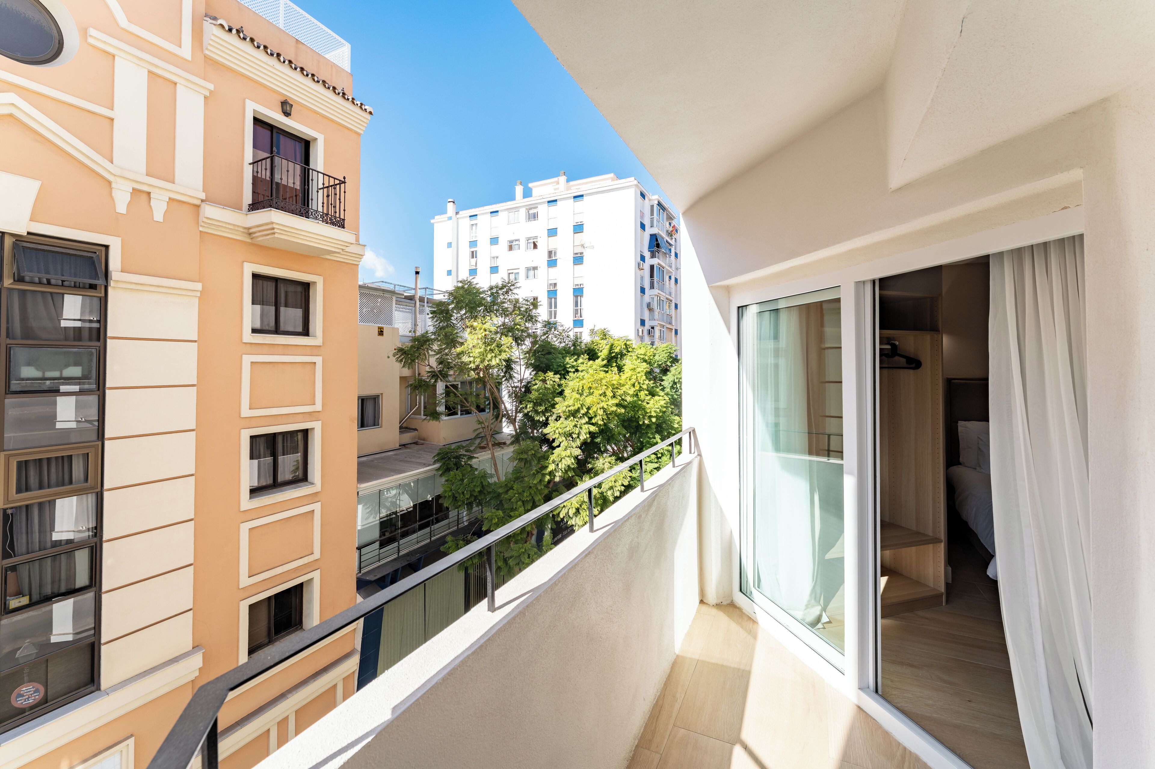 A balcony with a view of neighboring buildings and trees.
