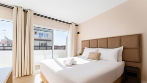 A hotel room with a large bed, a small bedside table, a view of the city through a balcony, and a window with curtains. - blanca maris (Fuengirola)