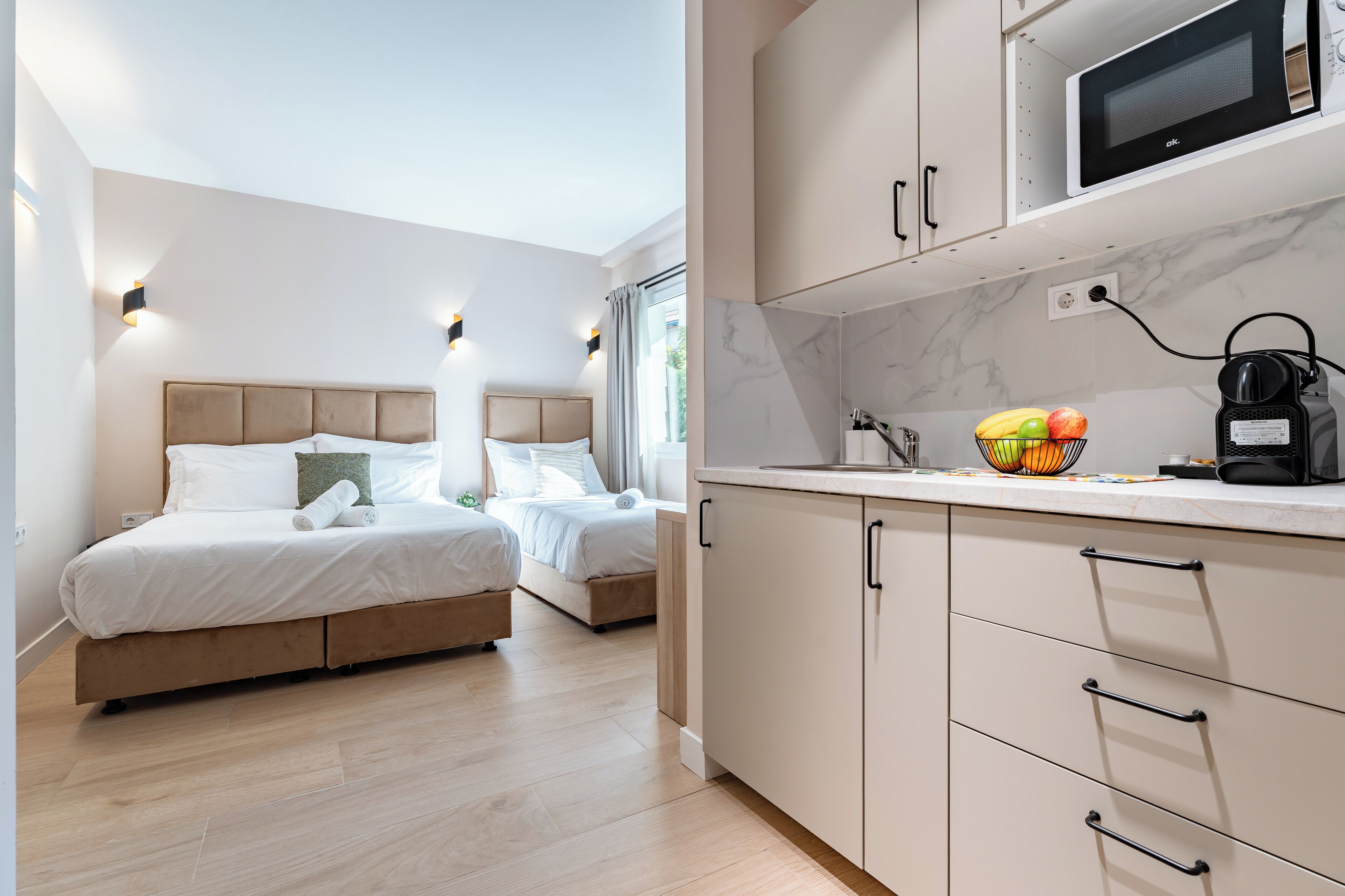 Habitación de hotel moderna con cama, mesitas de noche, microondas y un frutero en la encimera.