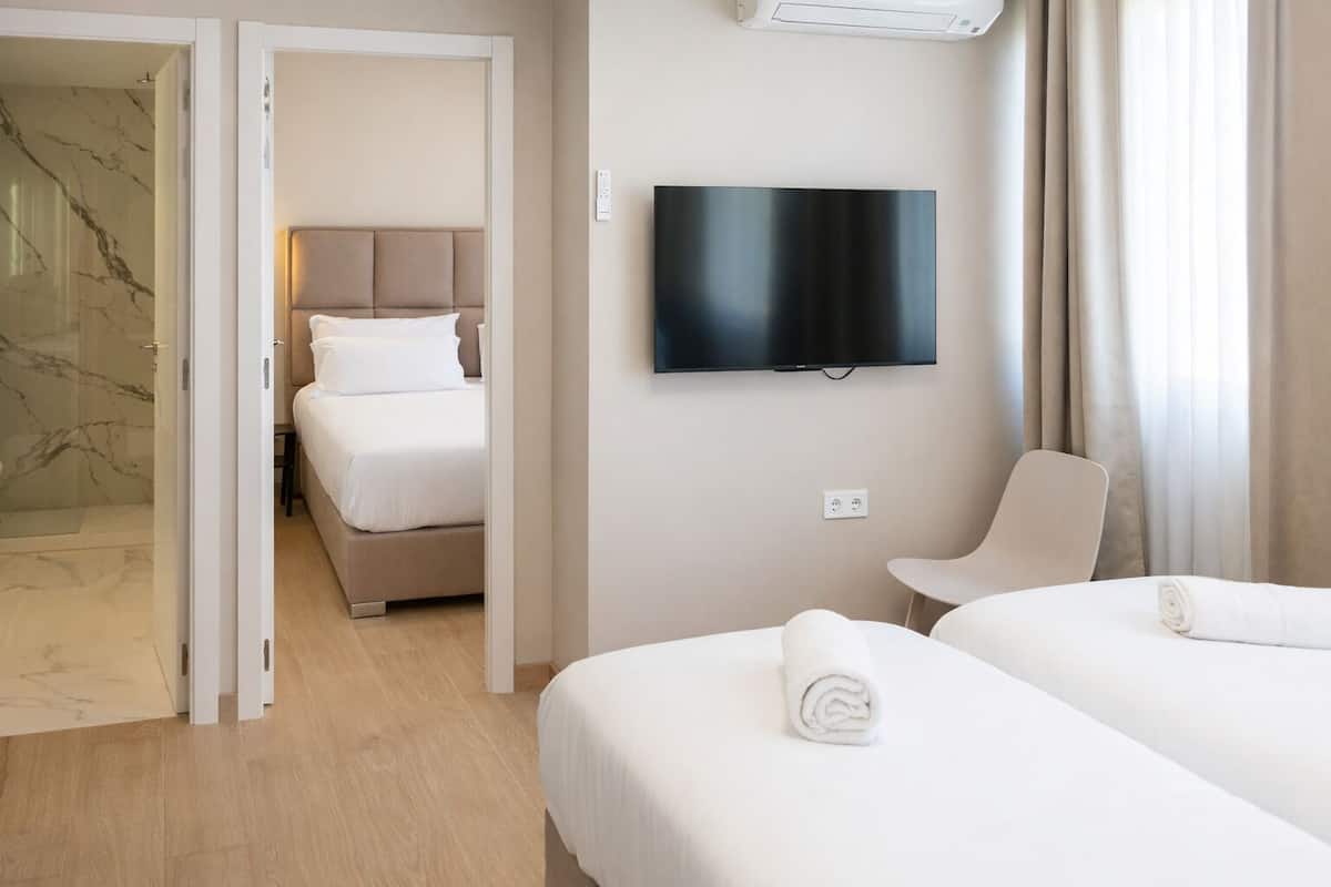 A hotel room with a bed, a TV, a chair, and a shower area.