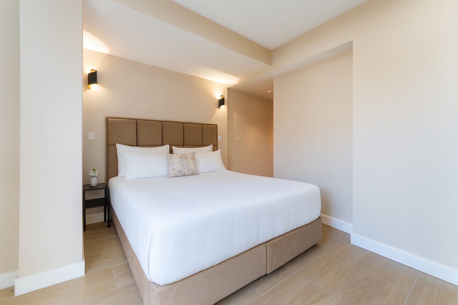 Une chambre moderne avec un grand lit, une table de chevet et des lampes fixées au mur.