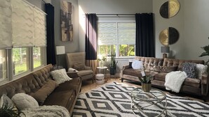 A spacious living room with a large window, a patterned rug, and two sofas.