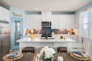 A modern kitchen with white cabinets, a central island, and a sink.