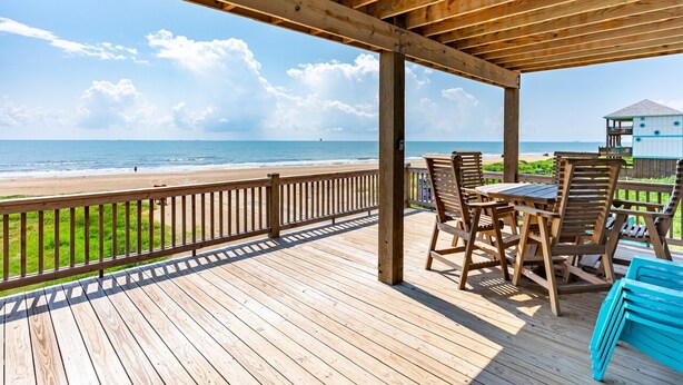 Eine Holzterrasse mit Blick auf Strand und Meer.