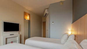 A hotel room with two beds, a TV, a wardrobe, and a wall-mounted air conditioner. - Transamerica Fit Aracruz (Aracruz)