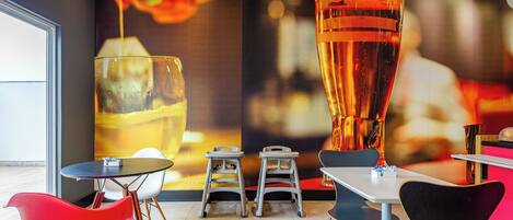 A modern restaurant interior with a large mural, a bar area, and contemporary seating.