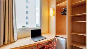 A hotel room with a laptop on a desk, a chair, a wardrobe with shelves, and a window with curtains. - Transamerica Fit Aracruz (Aracruz)
