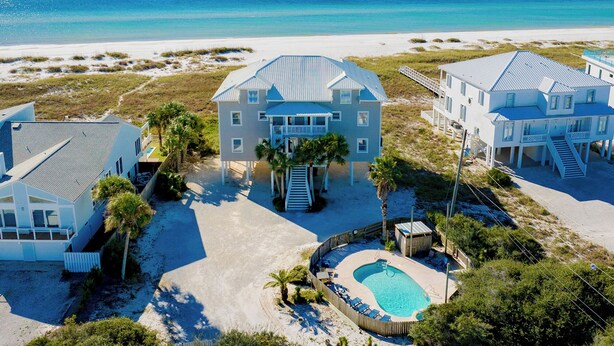 Une propriété située en bord de mer, comprenant plusieurs maisons, une piscine et offrant une vue sur la plage.