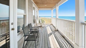 Une terrasse en bois avec des chaises et une vue sur l’océan.