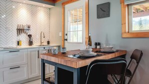Una cucina moderna con rivestimento a mosaico a spina di pesce, soffitto in legno e zona pranzo con tavolo e sedie in legno.