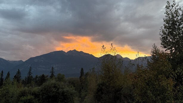 Una vasca idromassaggio con montagne sullo sfondo e un cielo nuvoloso.