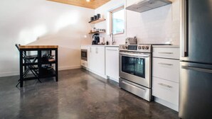 A modern kitchen with white cabinets, stainless steel appliances, and a wooden ceiling. - Unreal Mountain Views | Private Hot Tub | PÜR 3 (Golden)