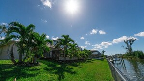 Un quartiere residenziale con una casa, palme, un molo e un corso d'acqua.