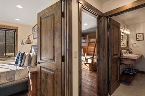 A bedroom with a bed, bedside lamp, and a window. - Mountain Escape | Hot Tub, Firepit, Movie Theatre + More! (Big Sky)