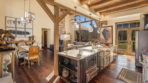 Una cocina amplia con una isla grande, vigas de madera y un muro de piedra decorativo.
