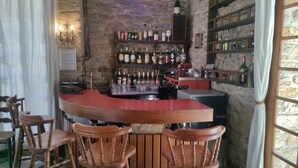 Un espace bar avec des chaises en bois, un comptoir et des étagères remplies de bouteilles.