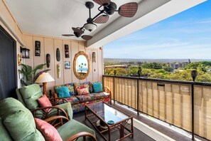 Ein Balkon mit einer Couch, Stühlen, einem Tisch und einem Deckenventilator.