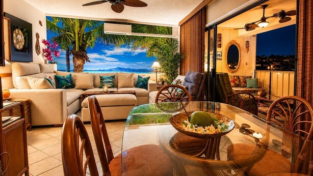 Uma sala de estar com um mural tropical, uma mesa de jantar com cadeiras e vista para o oceano.