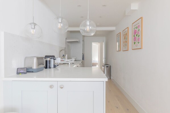 A modern kitchen with a central island, pendant lights, and framed botanical prints on the wall.