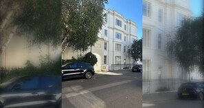 A street view with a building featuring classical architecture, a parked car, and a tree.