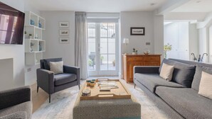 A modern living room with two sofas, a coffee table, and a bookshelf. - 2BD Hidden Gem in the Heart of Paddington (Greater London)
