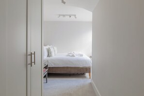A bedroom with a bed, a bedside table, and a wardrobe.