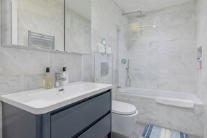 Un baño moderno con tocador blanco, inodoro, ducha y bañera.