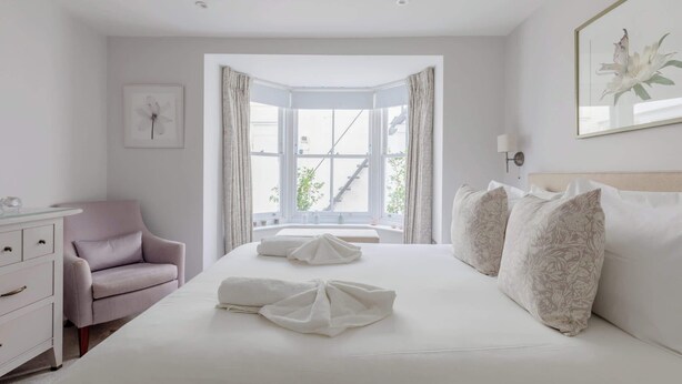 A hotel room with a bed, a chair, a desk, and a window with curtains. - 2BD Hidden Gem in the Heart of Paddington (Greater London)