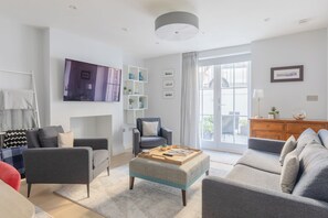Una sala de estar moderna con sofá, sillones, una mesa de centro y un televisor montado en la pared.
