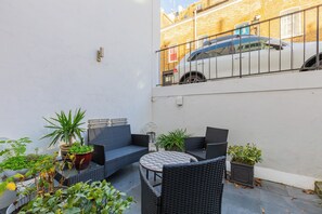 An outdoor seating area with wicker furniture and potted plants.