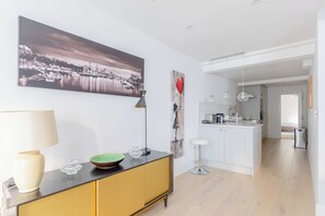 A modern kitchen with a central island, a dining area with a table and chairs, and a view of the cityscape through the window.