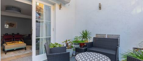 Une terrasse avec des meubles en osier, une table ronde et des plantes en pot.