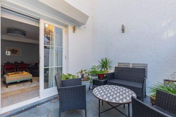 A patio with wicker furniture, a round table, and potted plants.