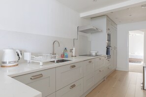 Una cocina moderna con lavabo, tetera y armarios de almacenamiento.