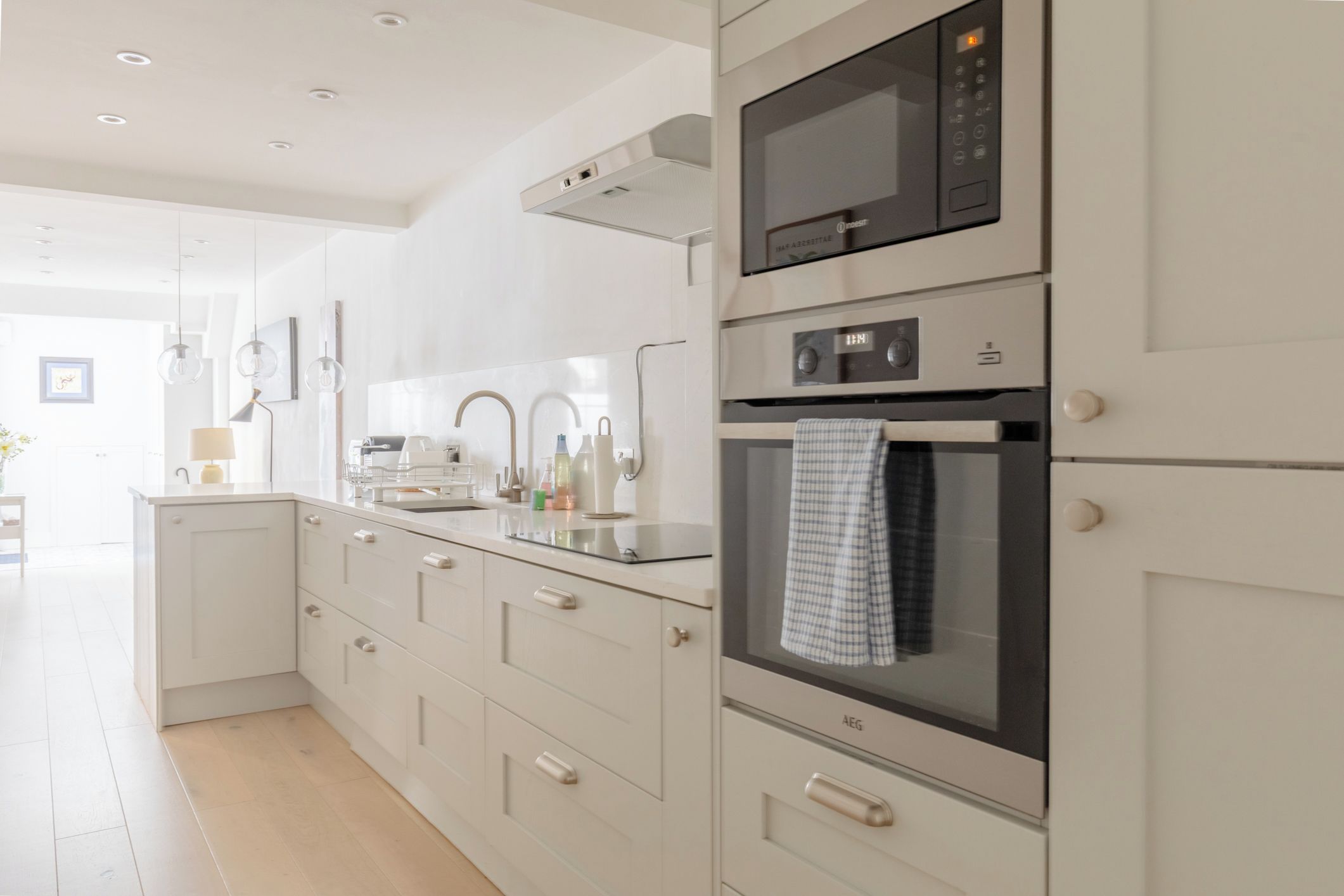 Een moderne keuken met een ingebouwde oven, magnetron en een roestvrijstalen spoelbak.